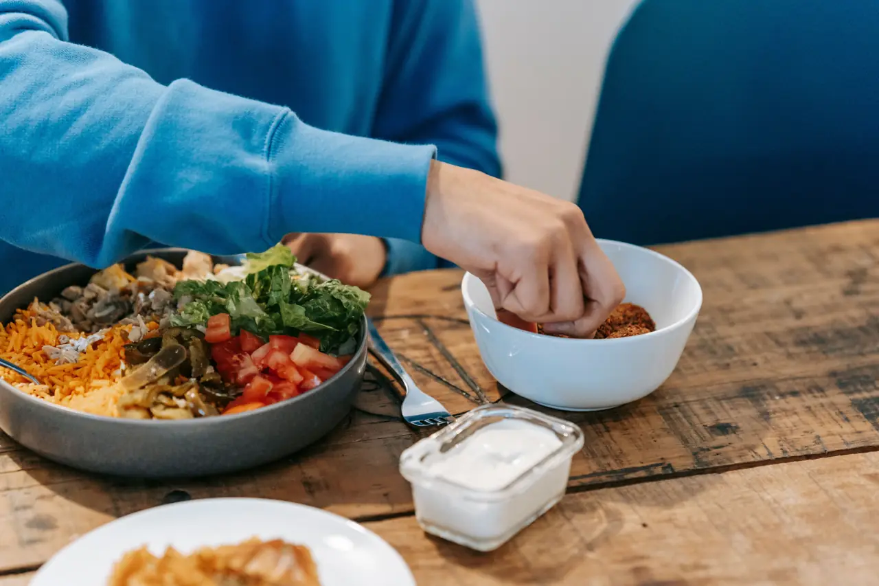 Reaching for a bowl at a wooden table set with fresh food
