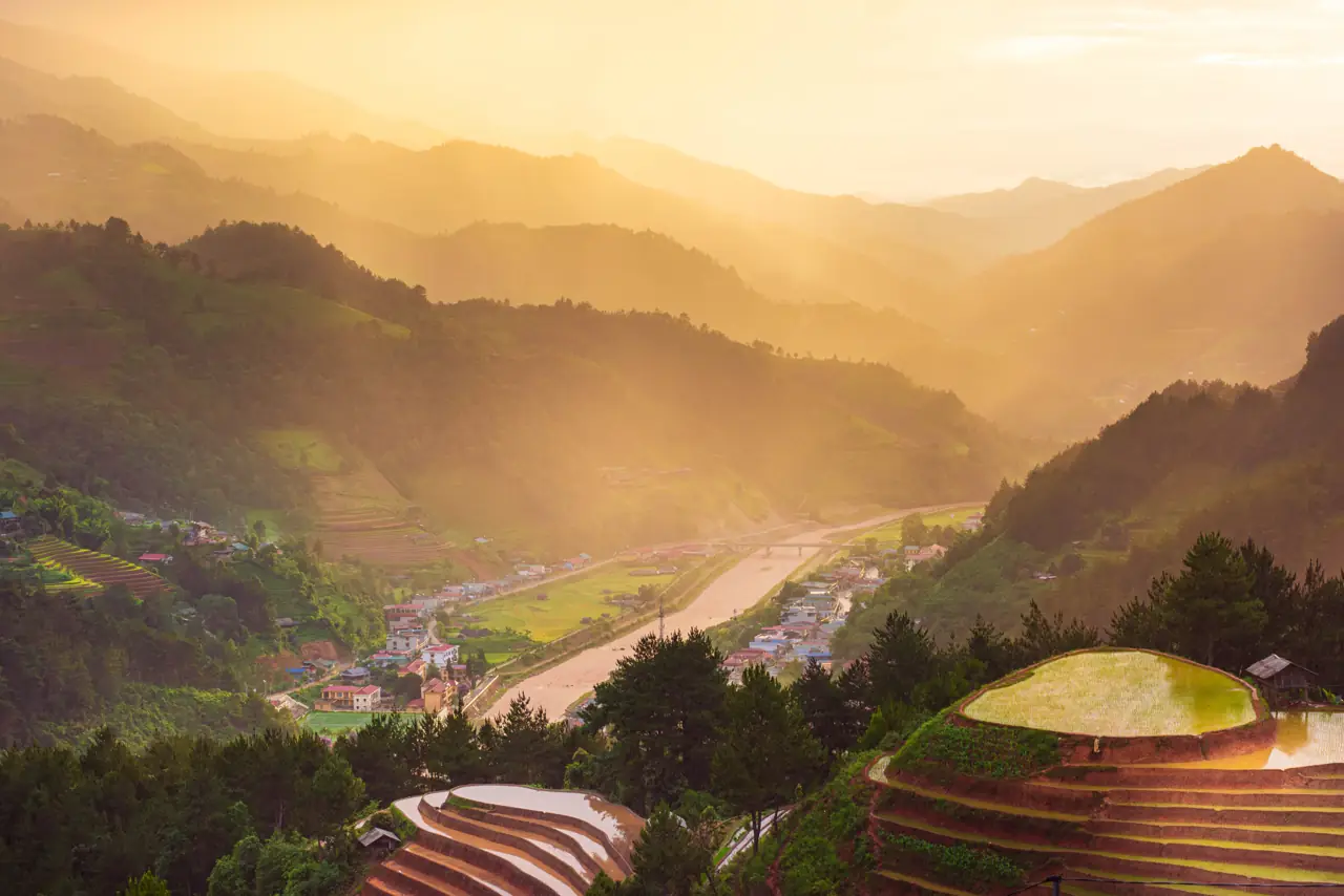 Rice terraces in a valley in golden morning mist
