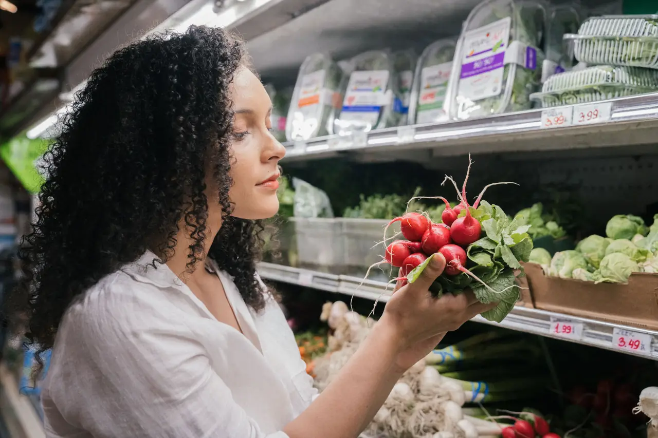 A shopper choosing fresh radishes in a grocery store