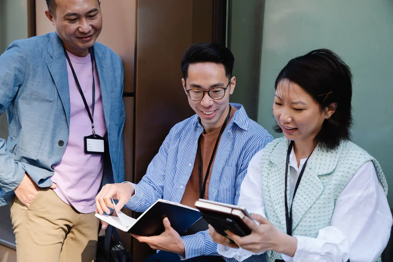 Three colleagues reading a notebook together